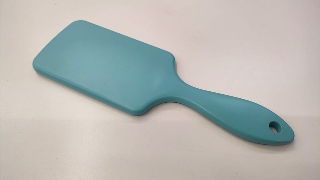 A light blue hairbrush with a rectangular head and a curved handle.