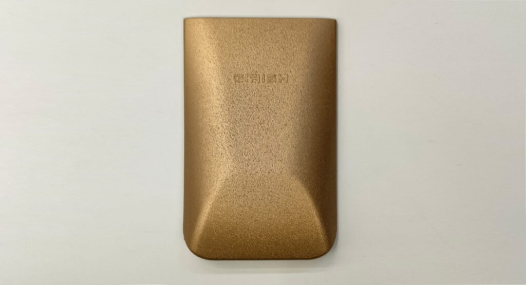 A close-up of a product with a sand-textured, gold-colored finish.