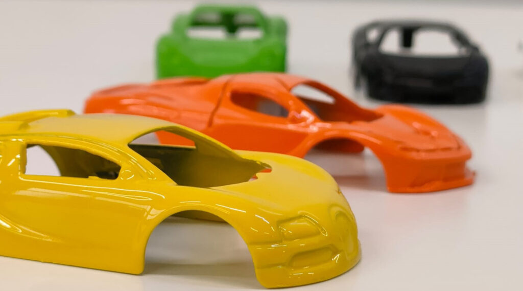 Several toy car models in various colors, showcasing the results of spray painting.